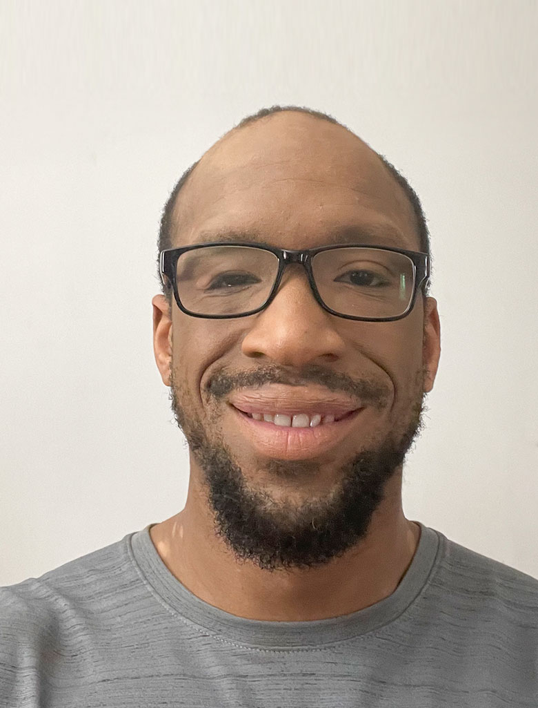 Personal trainer Ty wearing glasses and smiling in a headshot