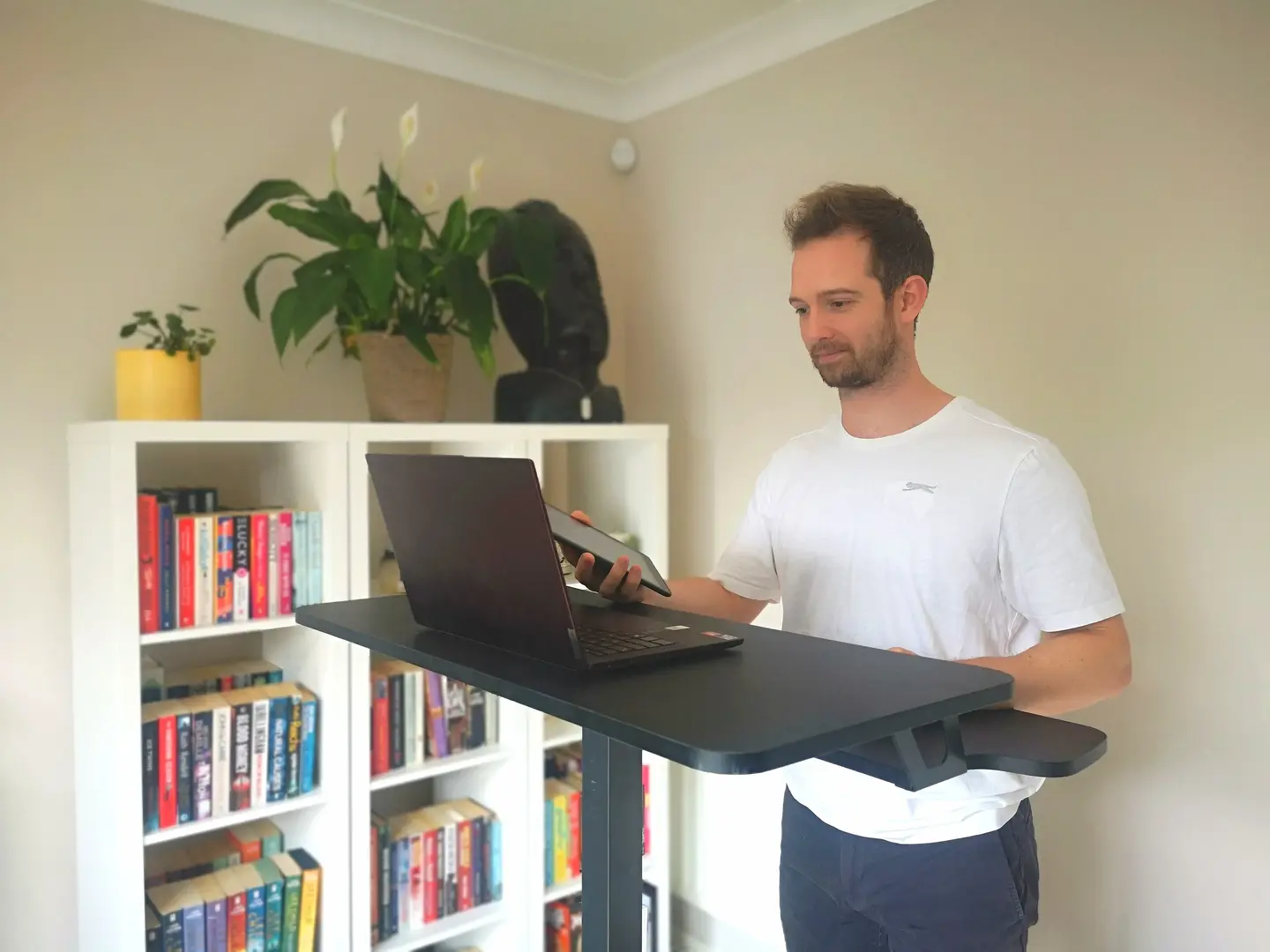 A personal trainer standing at his desk with his laptop and tablet ready to train a client