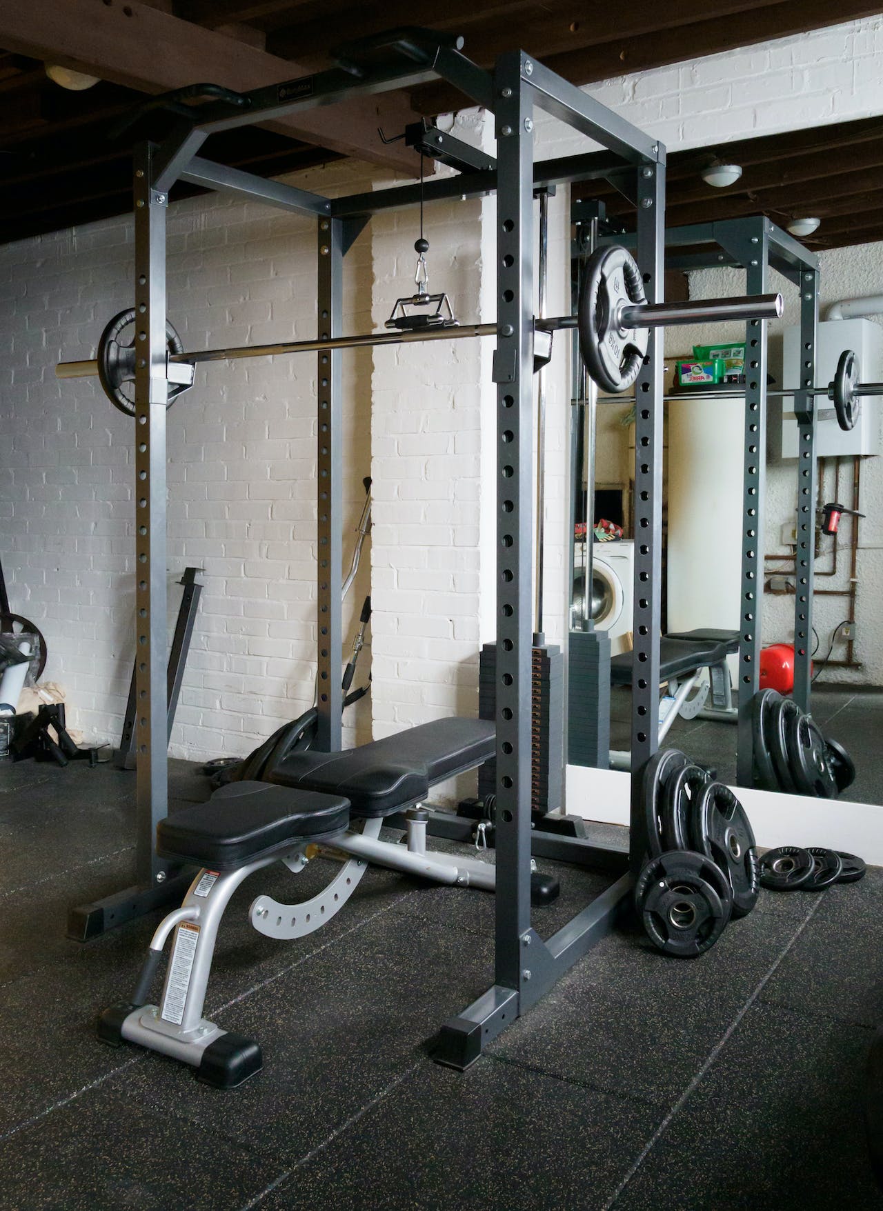 a power rack (or squat rack), with an adjustable bench and olympic barbell – staples of a home gym equipment list