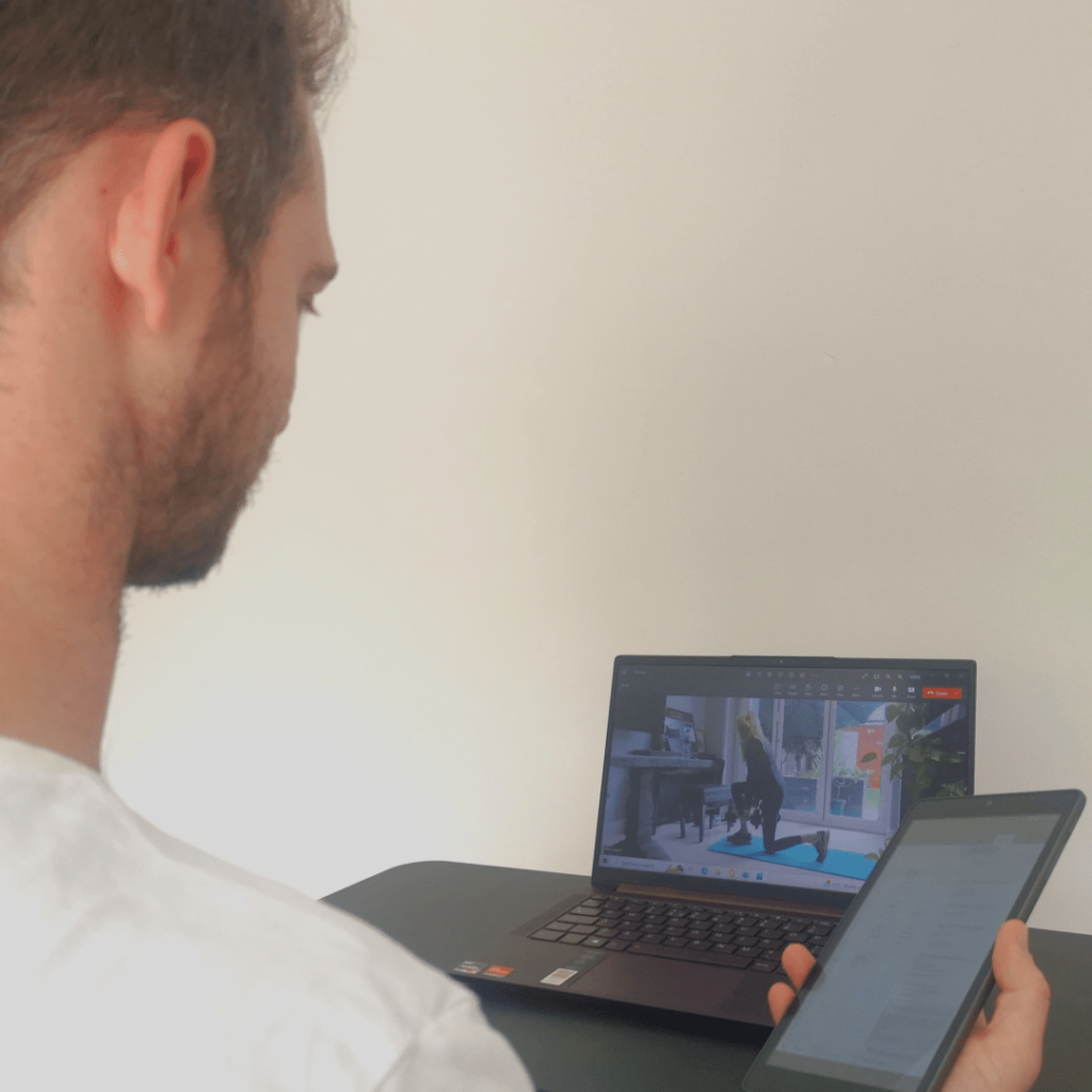 A virtual personal trainer with a client in a session via video call on a laptop. In the online personal trainer vs in person debate, video calling can be a suitable compromise