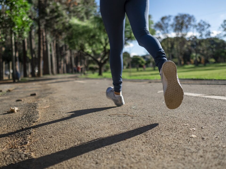 A woman running outdoors on a path, on her way to achieve fitness goals by being consistent