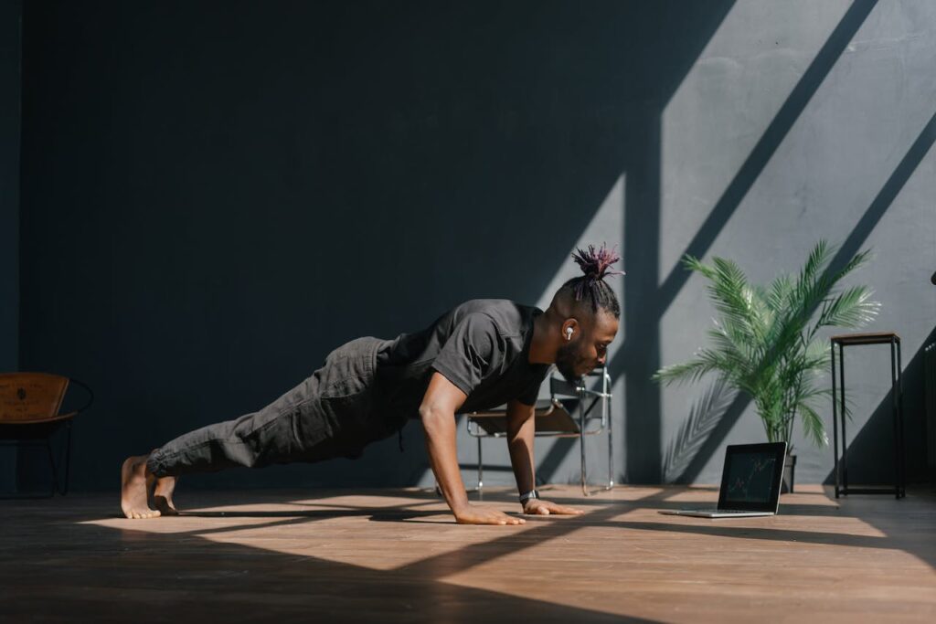 A man in black sports clothing making progress with his fitness ideas for beginners by doing press ups with good form in his home exercise area