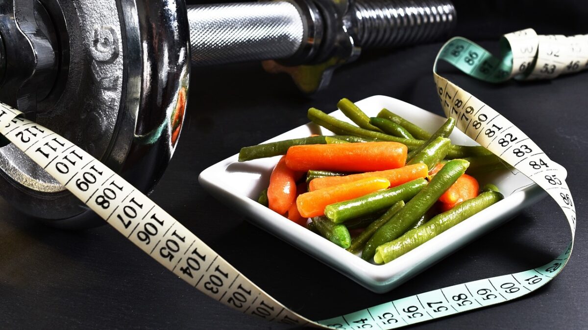 A photo of a dummbell, some mixed vegetables, and a tape measure, highlighting the different factors when choosing an online personal trainer for weight loss