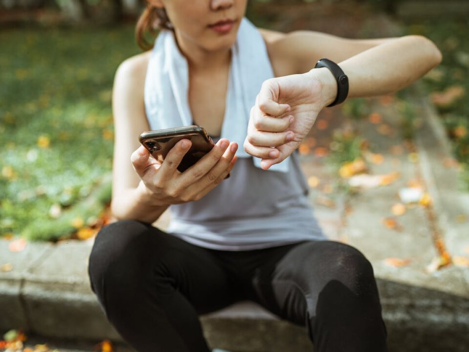 a client checking her heart rate on her watch after a run, about to log her workout in her fitness app with her online personal trainer benefits